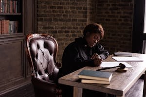 Black female judge in judicial robe writing at desk in an office setting, focusing on legal work.